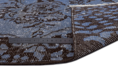 Load image 1 in gallery view. Blue and dark brown distressed floral pattern rug with a folded corner and a metal ruler for scale.