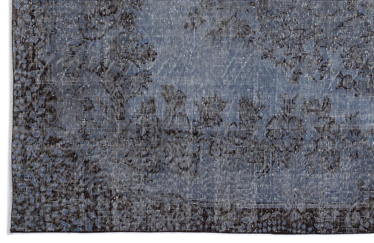 Blue and black distressed rug with a faded floral medallion pattern.