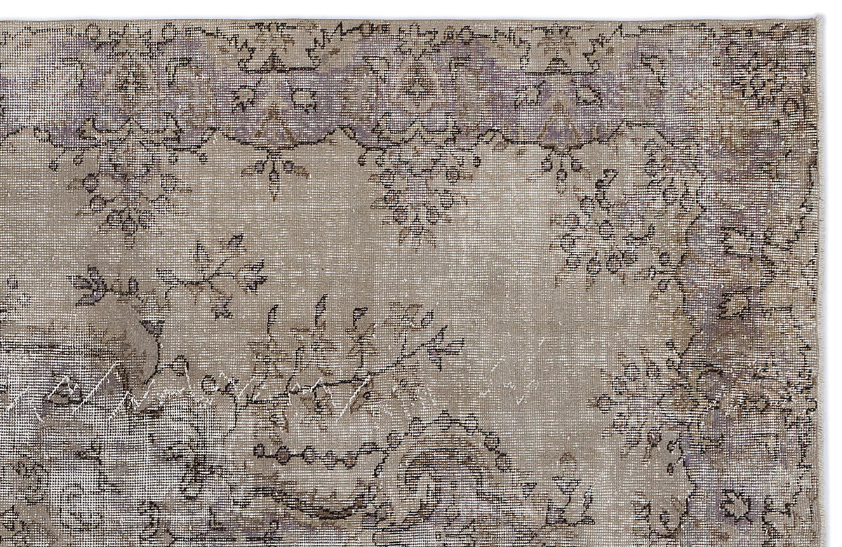 Distressed beige and lavender rug with a faded traditional floral medallion pattern.