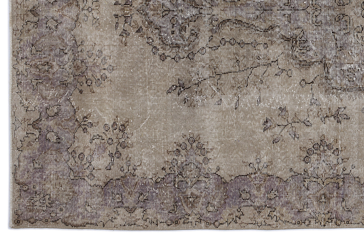 Taupe and grey distressed rug with a faded floral medallion pattern and a visible woven texture.