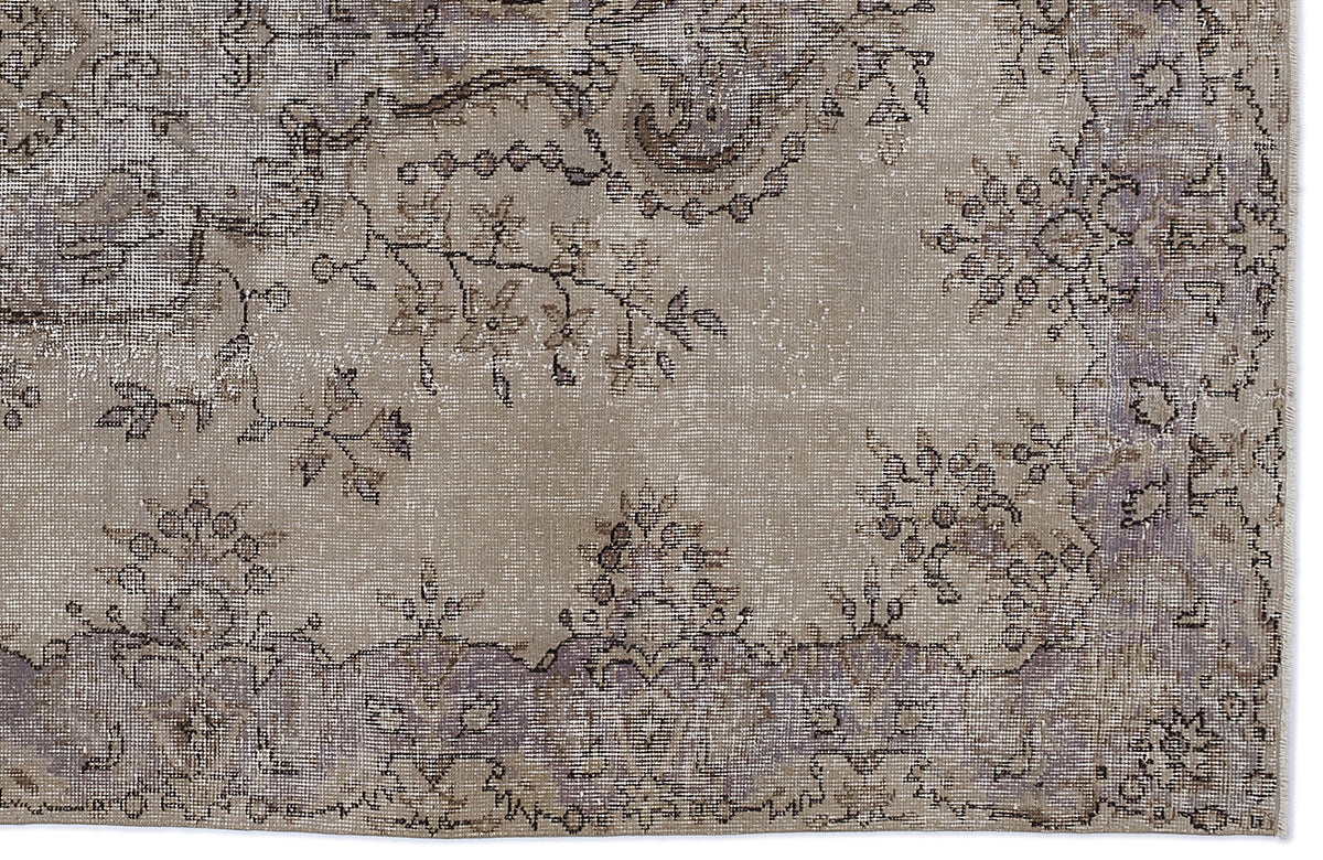 Taupe and grey distressed rug with a faded floral medallion pattern and intricate vine details.