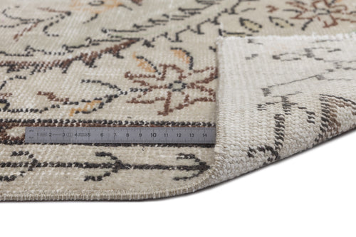 Load image 1 in gallery view. Beige rug with a distressed floral pattern in brown and charcoal, shown with a metal ruler for scale.