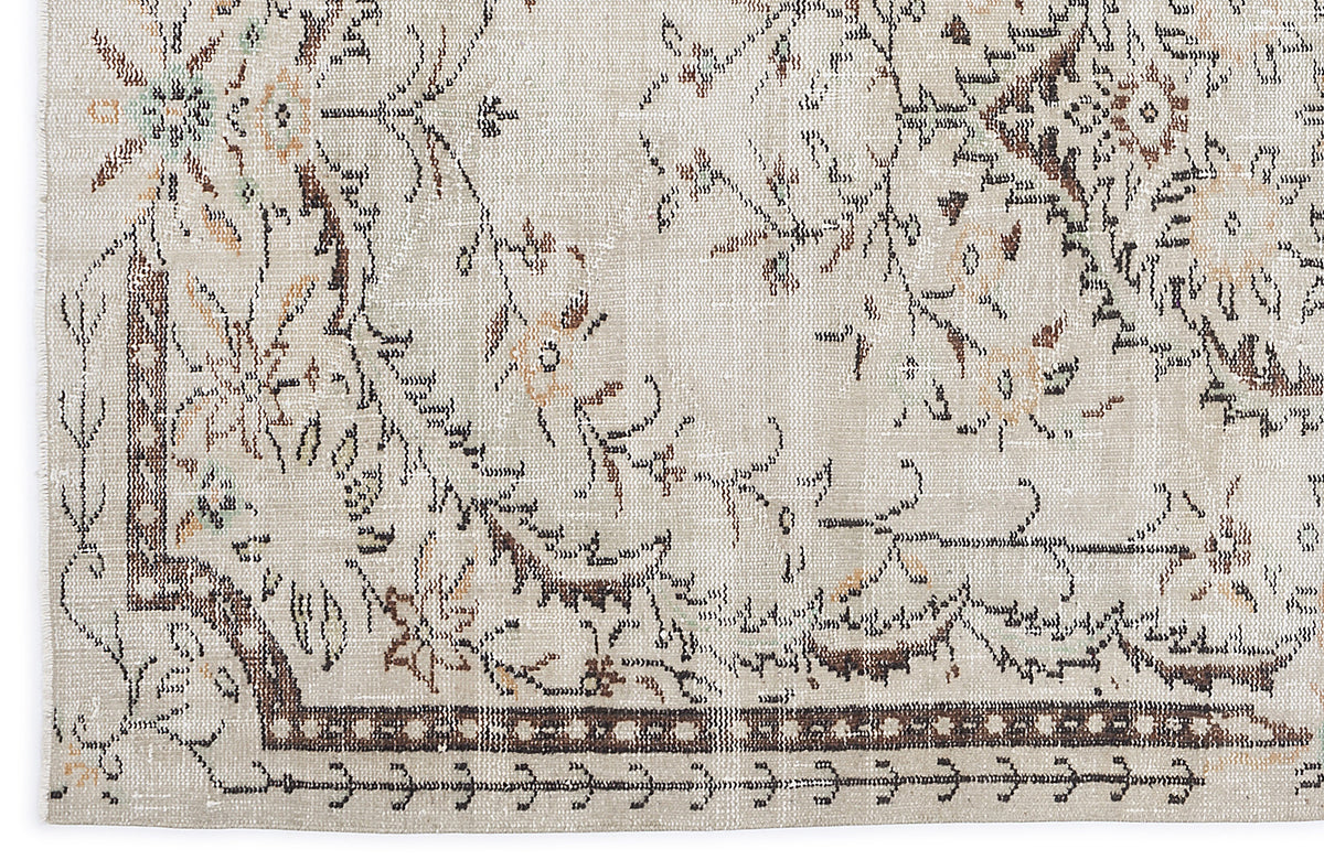 Beige rug with a distressed floral medallion pattern in brown, tan, and muted green accents.