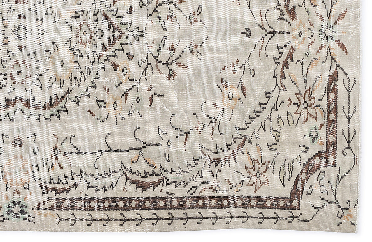 Beige and brown vintage-style rug with a distressed floral medallion pattern and a geometric border.