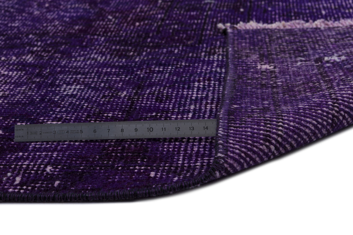 Deep purple distressed rug with a white grid pattern and a metal ruler showing pile height on a white background.