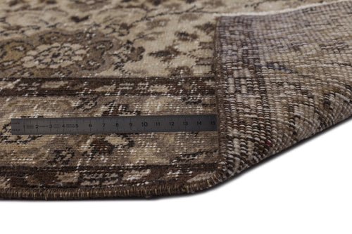 Load image 1 in gallery view. Brown and beige vintage-style rug with a floral medallion pattern, shown folded to reveal the woven backing and a ruler.