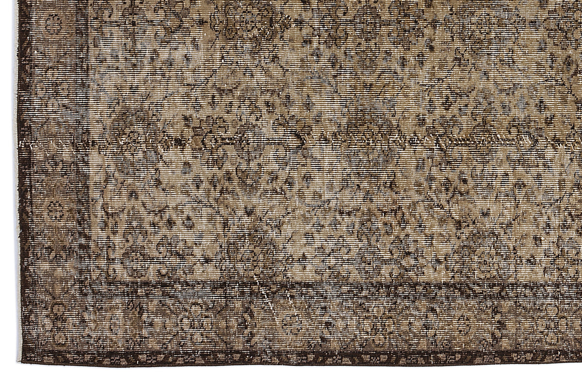 Dark brown and beige vintage-style rug with a distressed floral medallion pattern and a detailed border.
