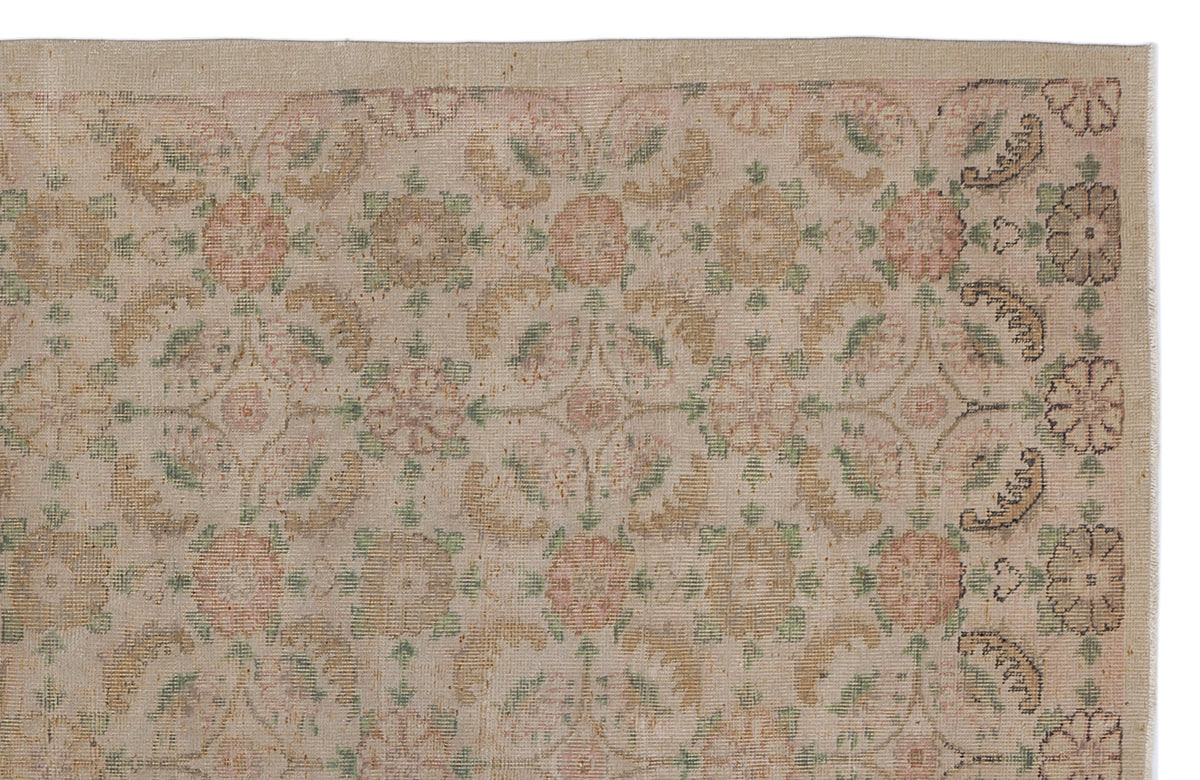 Beige vintage-style rug with a faded floral medallion pattern in muted pink, green, and tan tones.