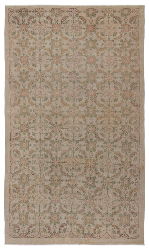 Load image 1 in gallery view. Beige rug with a faded, repeating floral medallion pattern in muted tones of sage green and dusty rose.