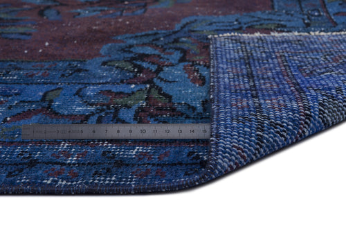 Load image 1 in gallery view. Blue and burgundy traditional patterned rug with a corner folded over, showing the woven backing and a metal ruler.