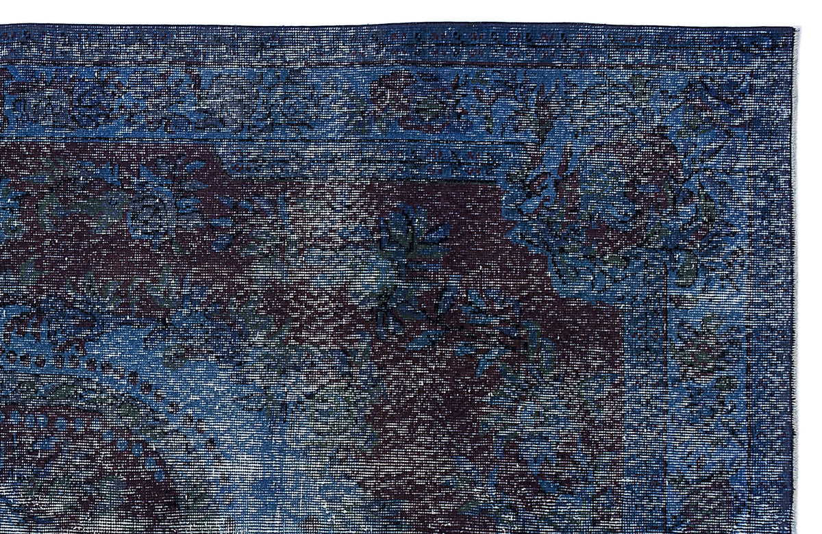 Deep blue and dark purple distressed rug with a traditional floral medallion pattern and a detailed border.