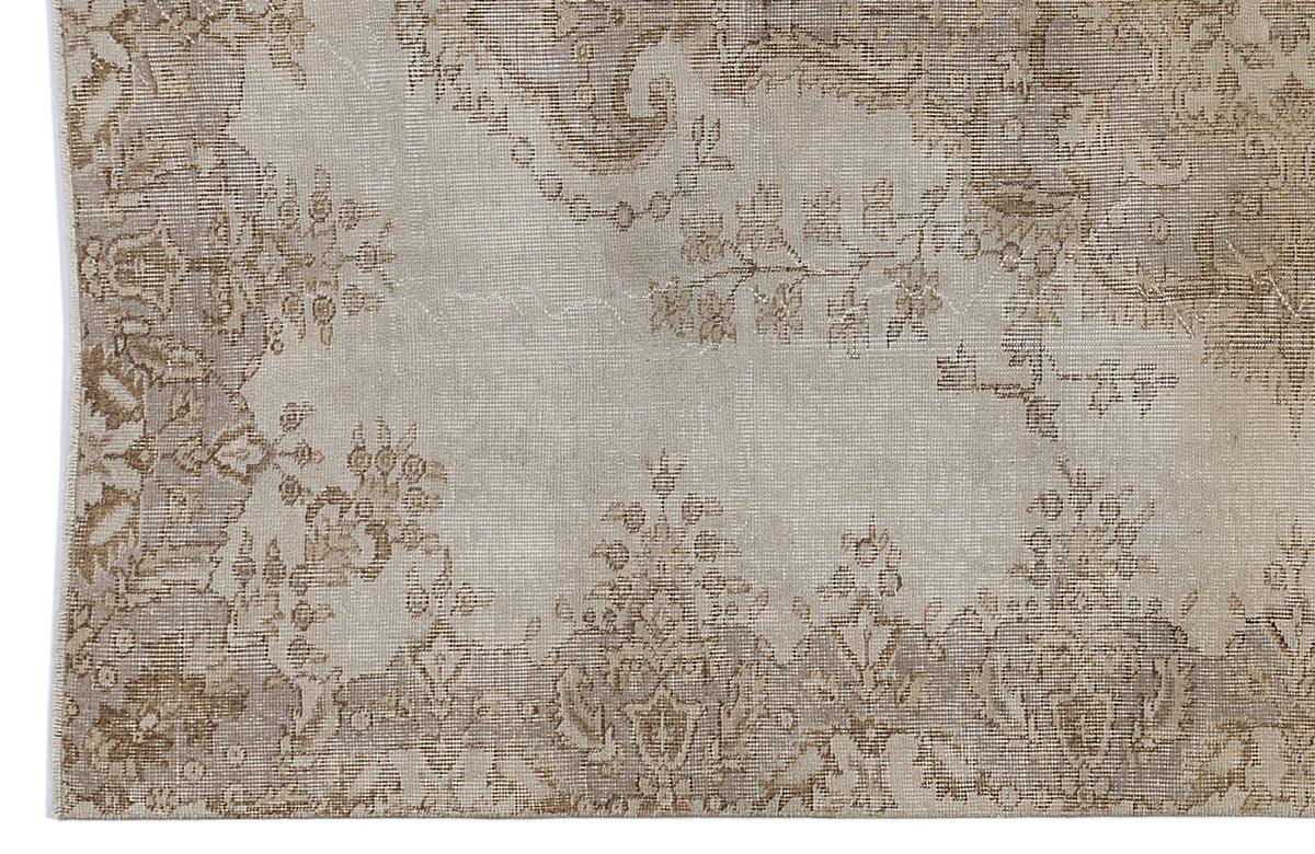 Beige and taupe vintage-style rug with a faded floral medallion pattern on a white background.
