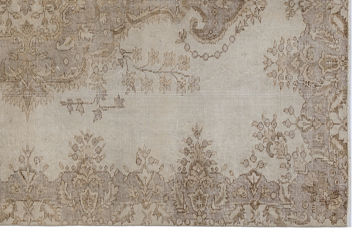 Beige and taupe rug with a faded, traditional floral medallion pattern and distressed texture.