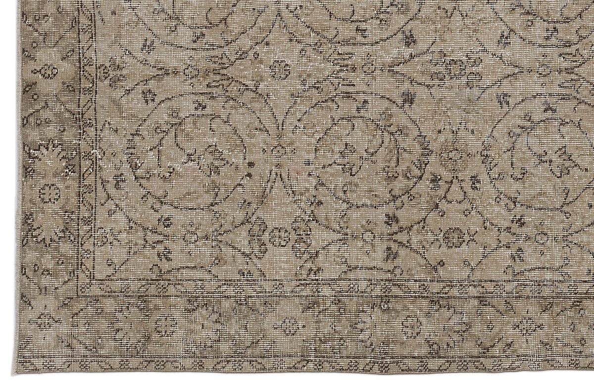 Taupe and brown vintage-style rug with a distressed floral medallion pattern and a decorative border.