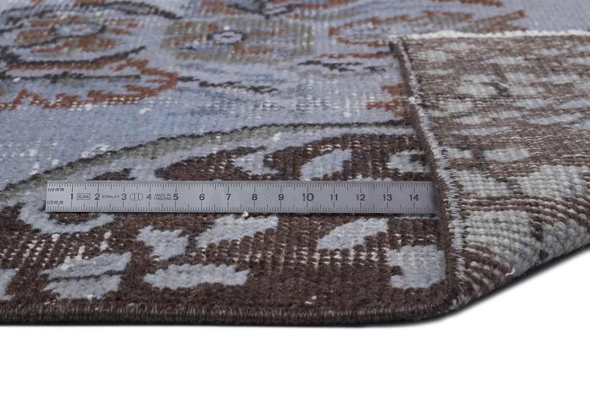 Blue and brown distressed traditional rug with a folded corner and a metal ruler for scale.