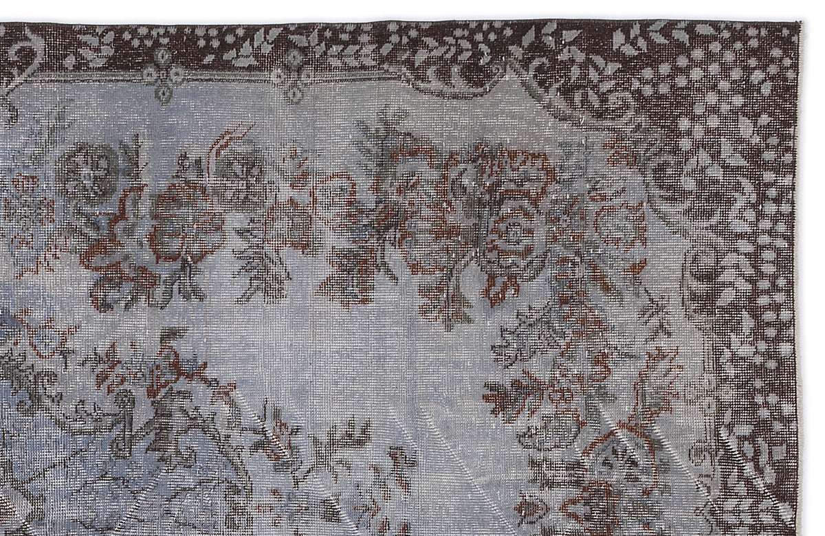 Distressed blue and brown rug with a traditional floral medallion pattern and a dark, intricate border.