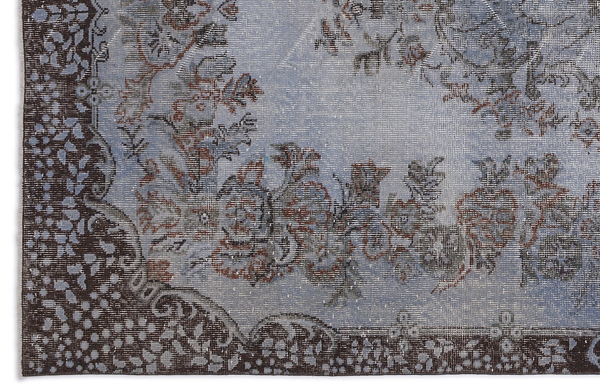 Distressed light blue rug with a dark brown floral border and central medallion pattern.