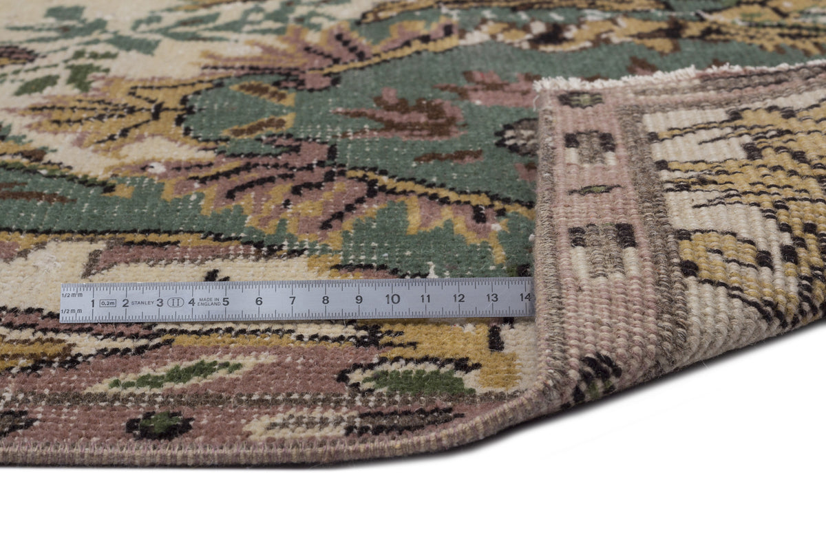 Sage green, cream, and muted pink traditional rug with a floral pattern, shown with a metal ruler for scale.