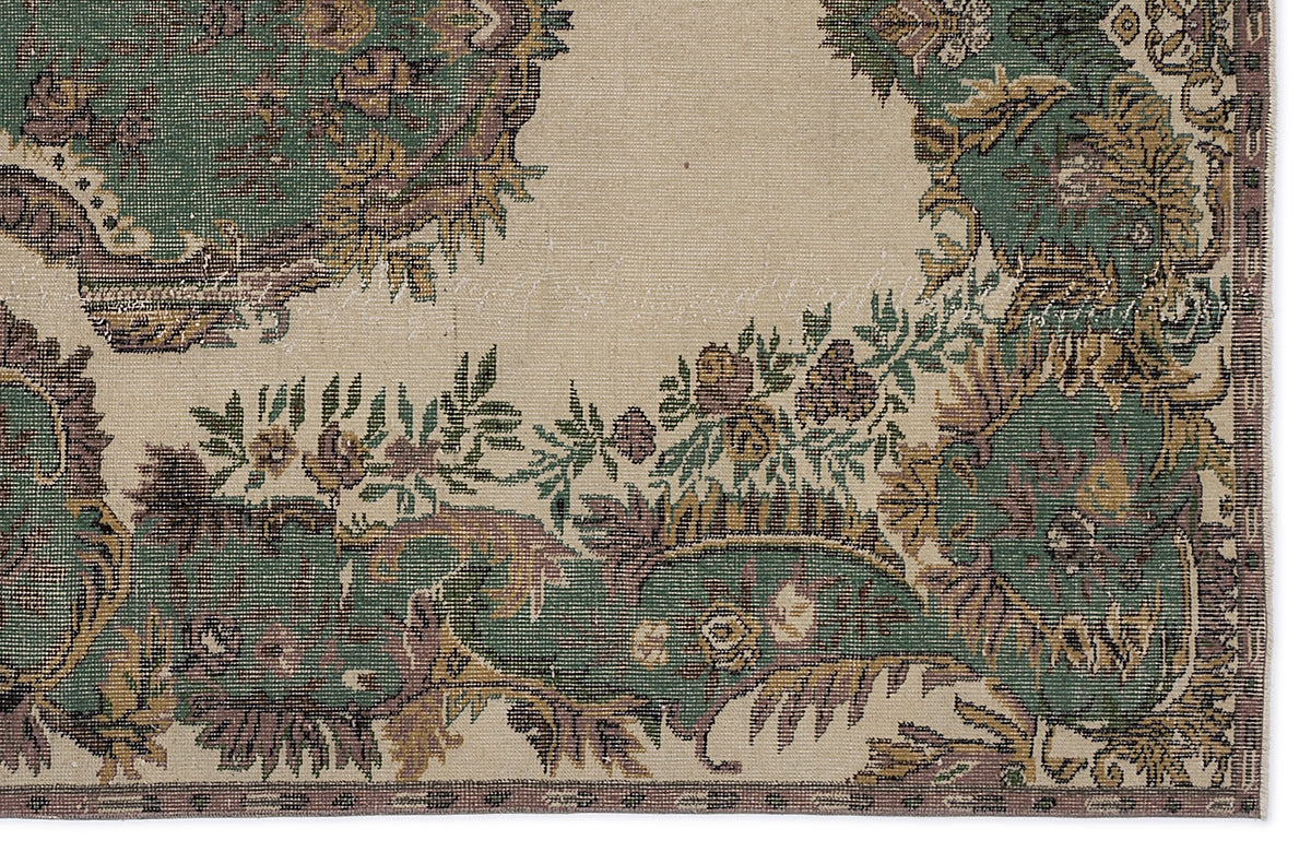 Beige rug with a distressed traditional floral medallion pattern in shades of forest green, mauve, and gold.