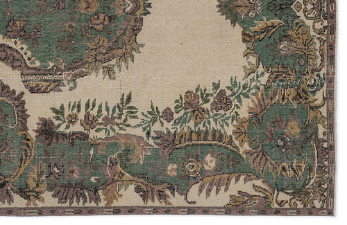Load image 1 in gallery view. Beige rug with a distressed traditional floral medallion pattern in shades of forest green, mauve, and gold.
