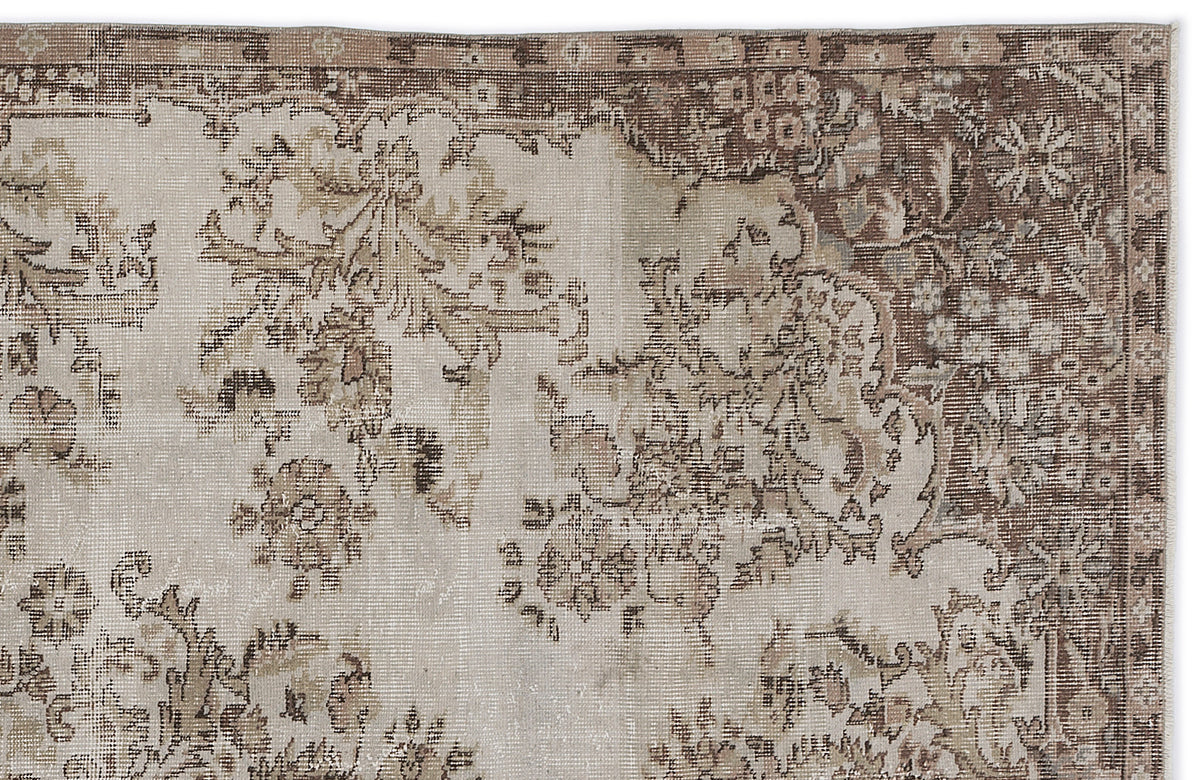 Beige and brown vintage-style rug with a distressed floral medallion pattern and a detailed border.