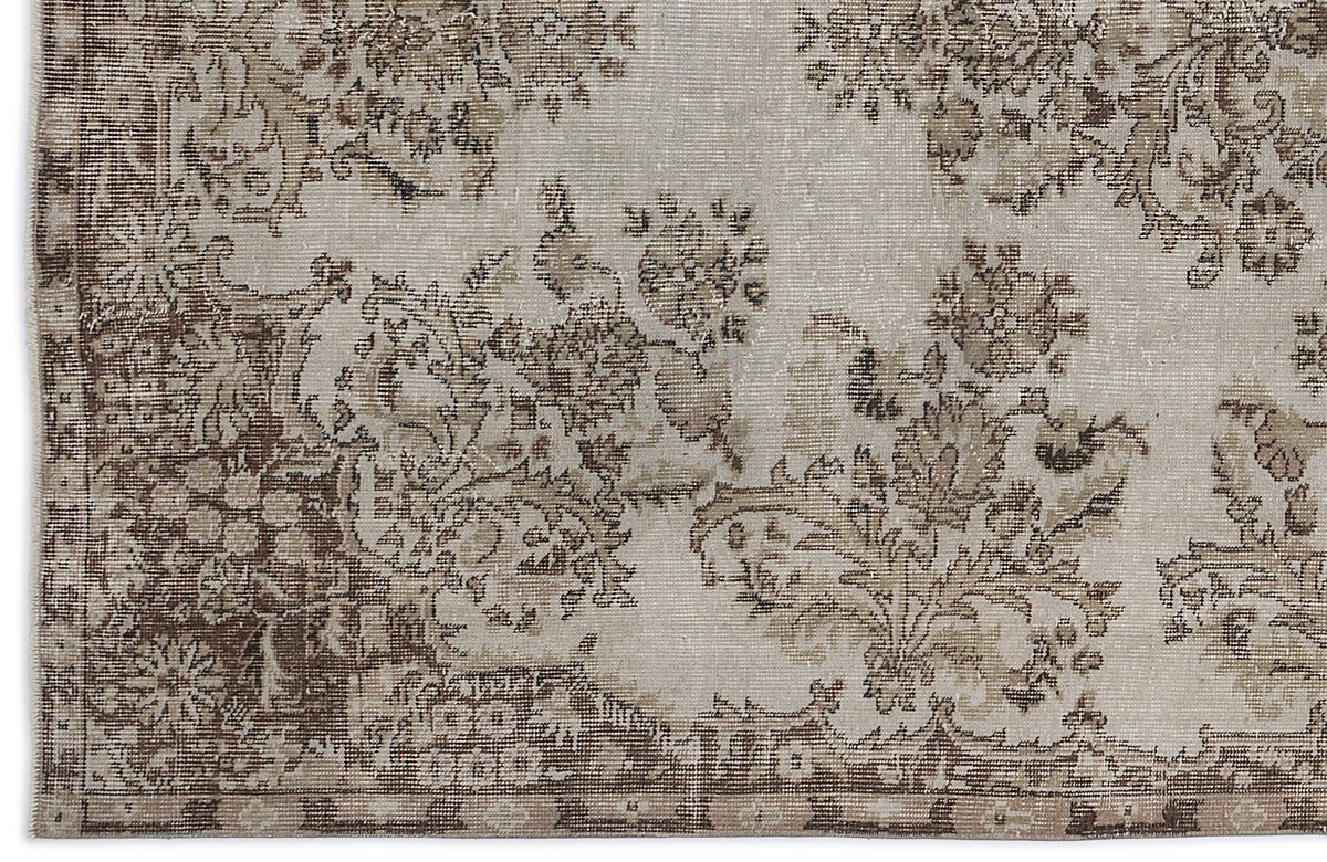 Beige and brown distressed rug with a faded floral medallion pattern and a decorative border.