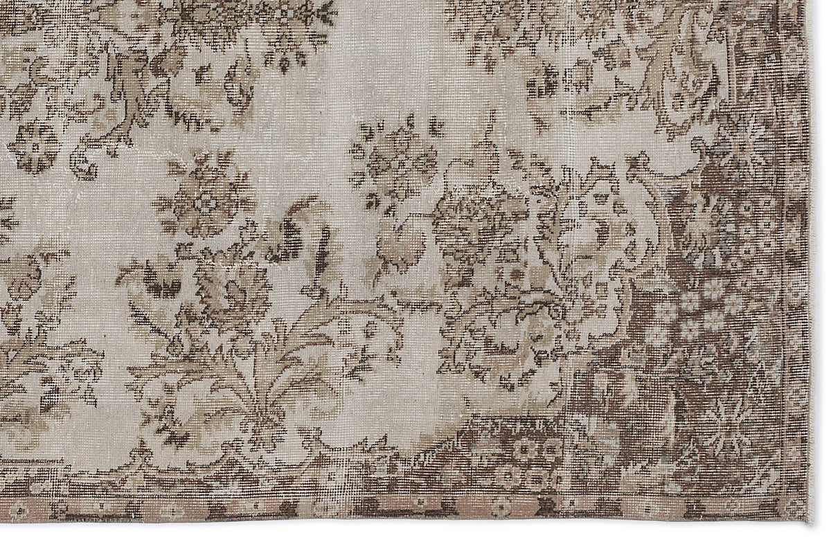 Beige and brown distressed rug with a faded floral medallion pattern on a white background.