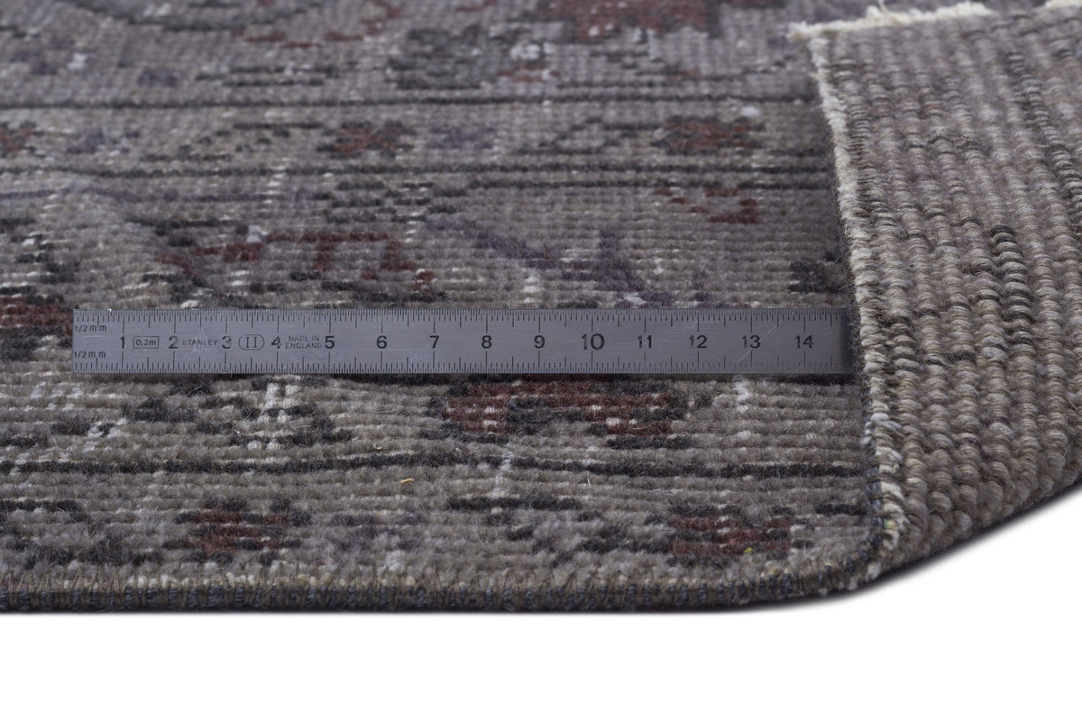 Grey and brown distressed traditional rug with a folded corner and a metal ruler for scale.