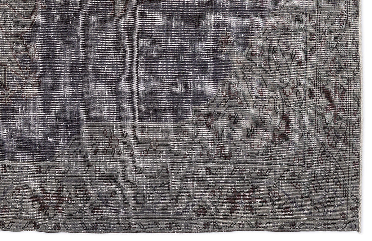 Charcoal and grey distressed rug with a faded traditional floral border and medallion corner detail.