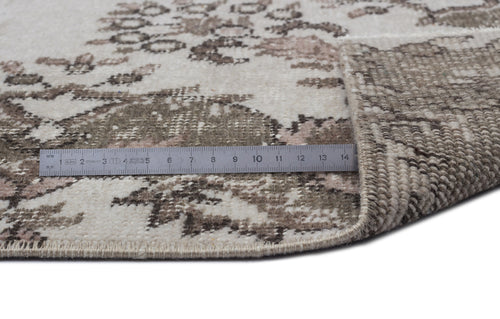 Load image 1 in gallery view. Cream and taupe distressed floral rug with a folded corner and a metal ruler showing scale on a white background.