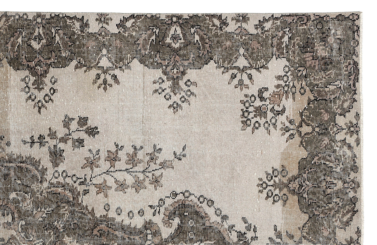 Distressed beige and charcoal grey rug with a traditional floral border and central medallion motif.