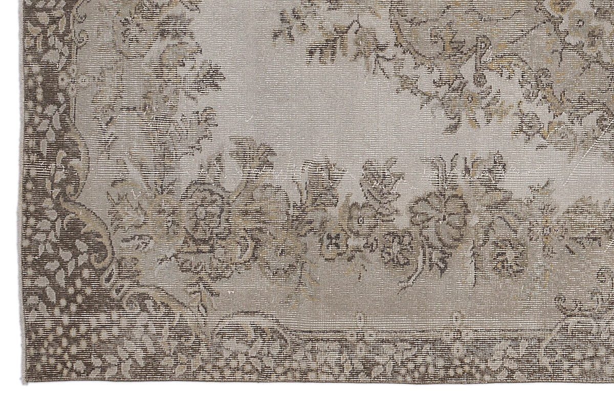 Taupe and beige rug with a distressed floral medallion pattern and a detailed border.