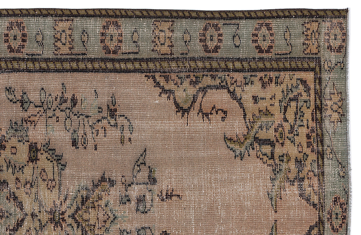 Distressed beige and sage green rug with a traditional floral medallion border and central botanical motifs.