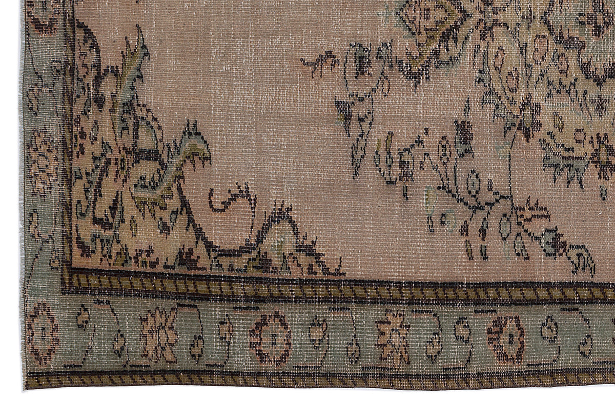 Distressed beige rug with a faded floral medallion pattern and a sage green border featuring geometric motifs.