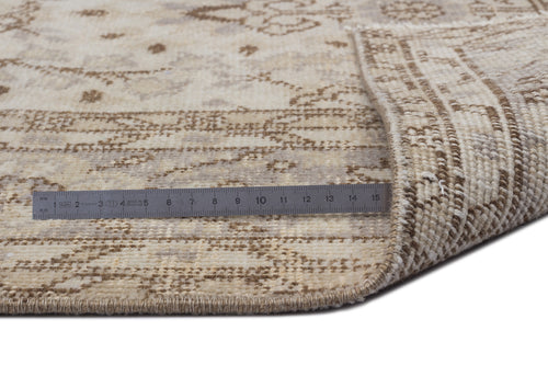Load image 1 in gallery view. Beige and cream distressed traditional rug with a folded corner and a metal ruler for scale on a white background.