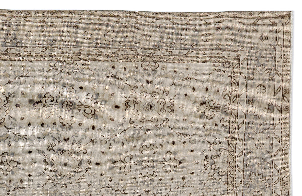 Beige and grey traditional rug with a distressed floral medallion pattern and a geometric border.