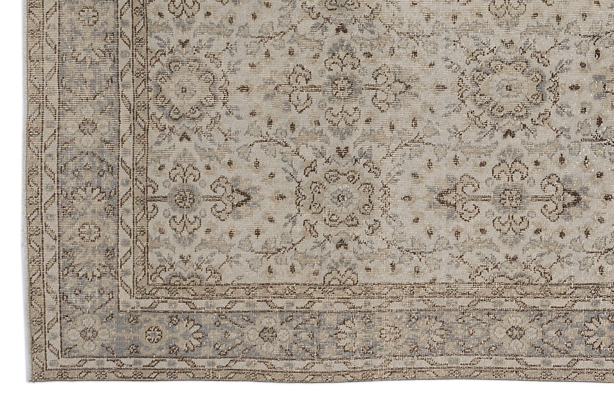 Beige and grey traditional rug with a distressed floral medallion pattern and a geometric border.