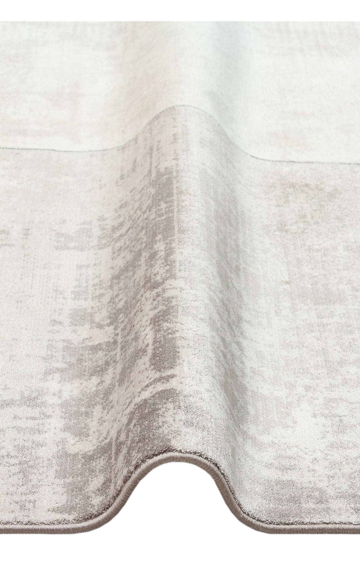 Light gray and white area rug with a distressed, abstract texture, shown folded against a white background.