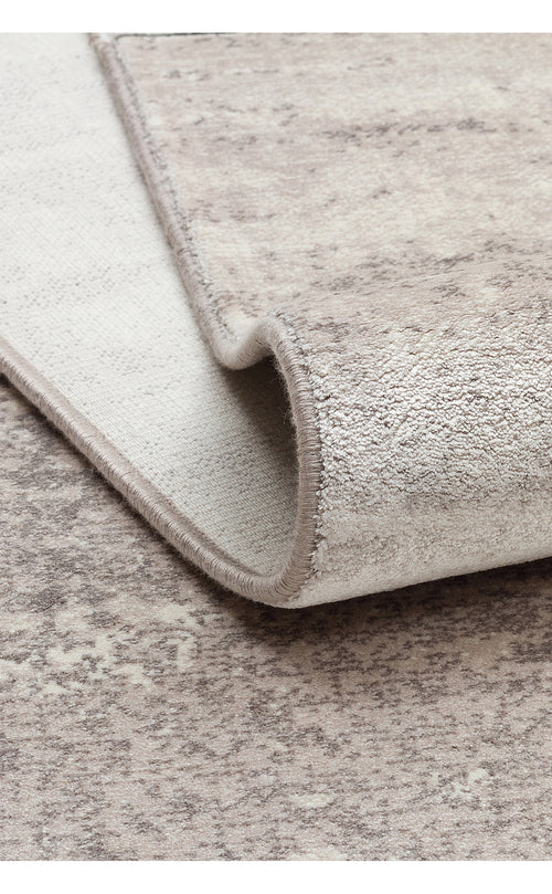 Load image 1 in gallery view. Beige and taupe area rug with a distressed, mottled texture, shown folded to reveal the woven backing.