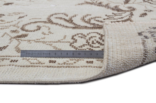 Load image 1 in gallery view. Cream rug with brown floral pattern, shown with a metal ruler for scale and a corner folded to reveal the backing.