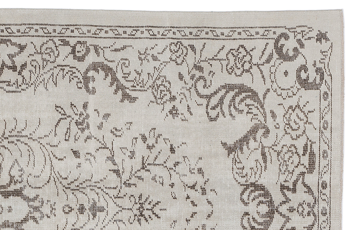 Beige rug with a dark brown floral and vine pattern in a traditional woven style on a white background.