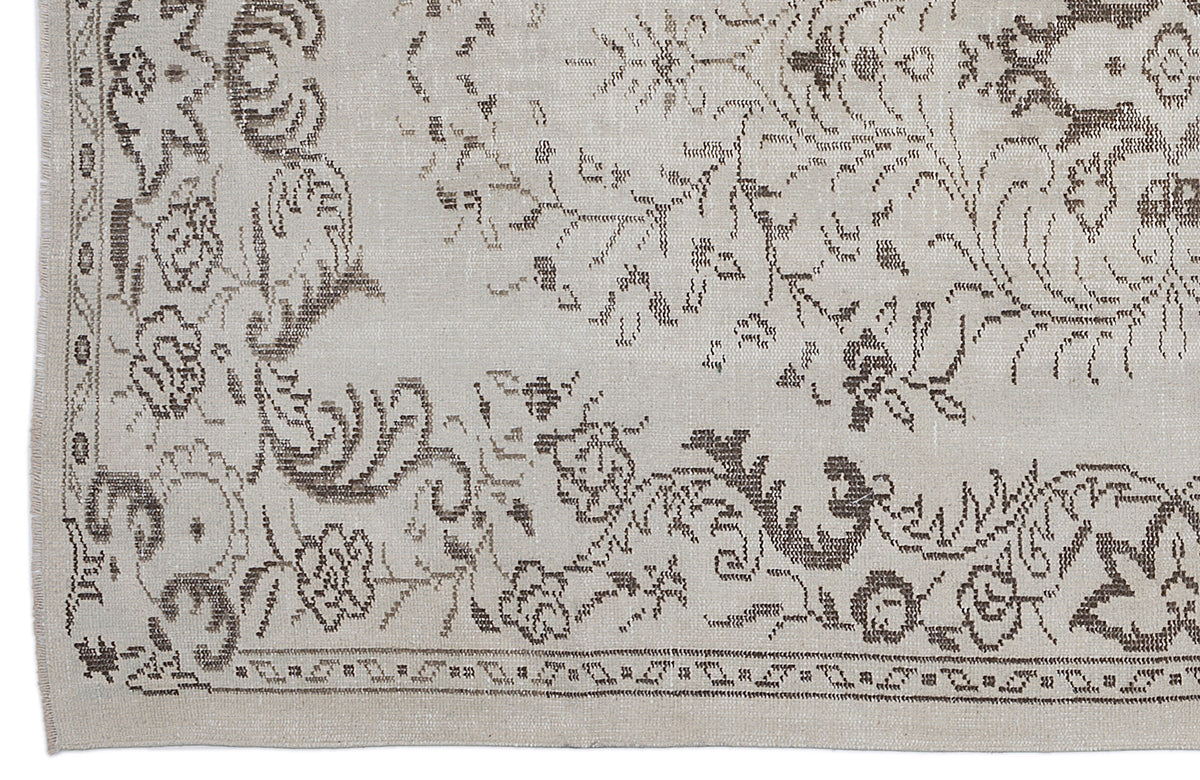 Beige rug with a distressed brown floral medallion pattern and a decorative border.