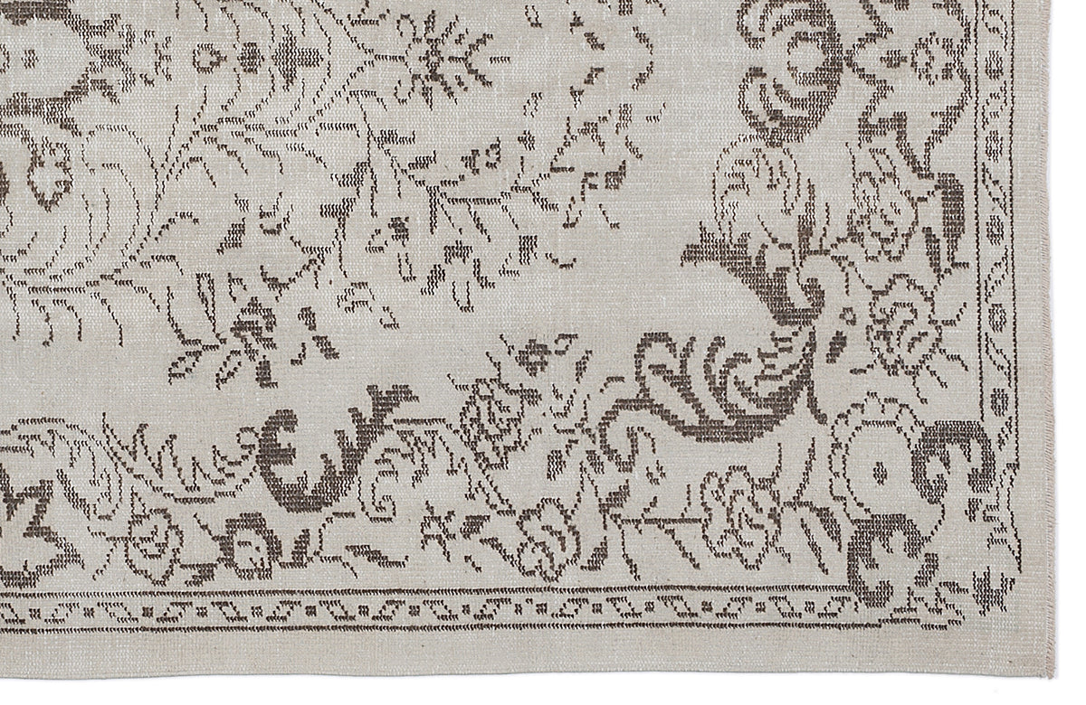 Beige and taupe rug with a distressed floral medallion pattern and a decorative border.