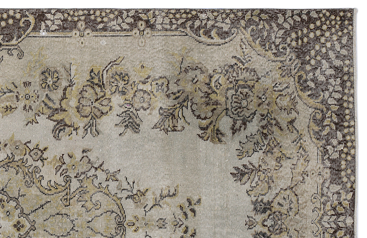 Distressed beige and brown rug with a traditional floral medallion pattern and a dark decorative border.