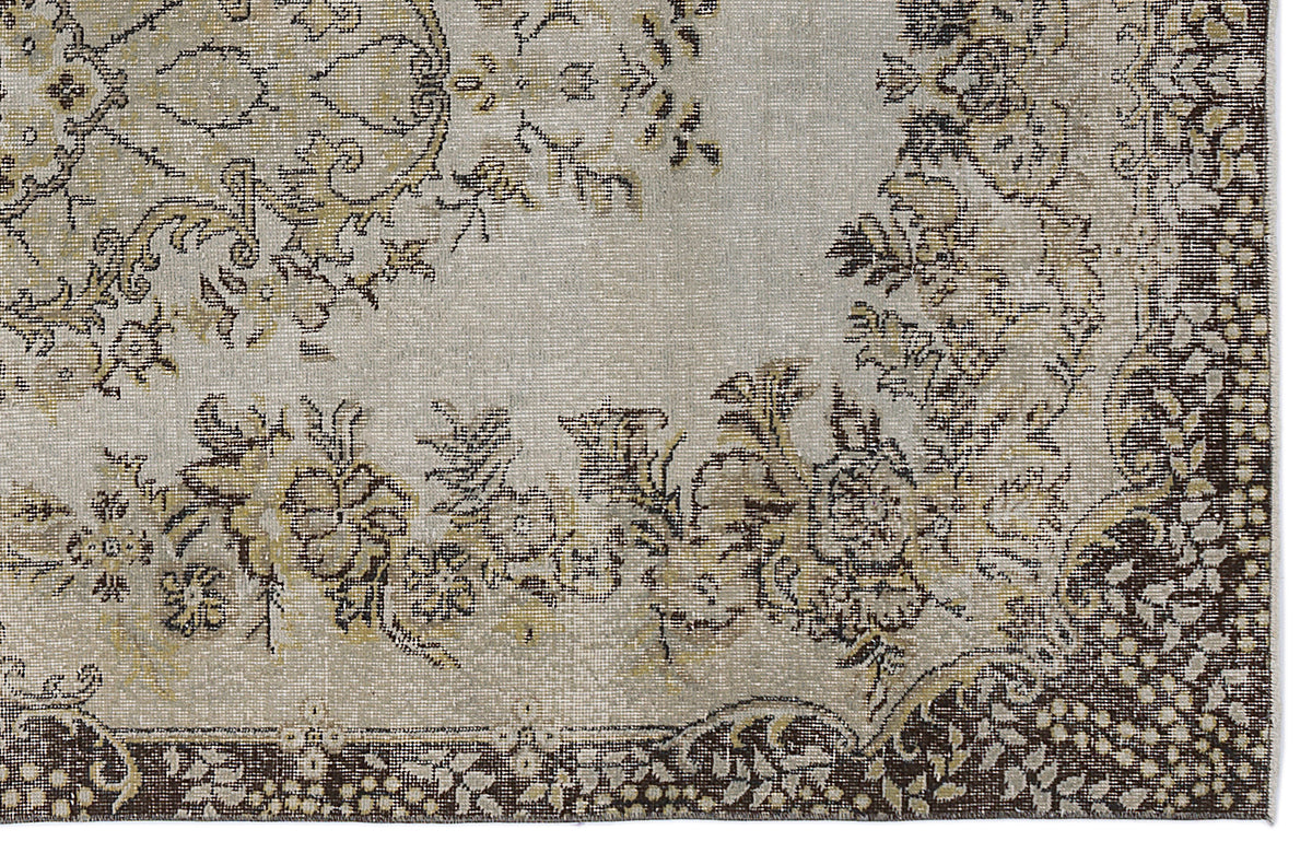 Distressed grey, beige, and dark brown rug with a traditional floral medallion pattern and ornate border.