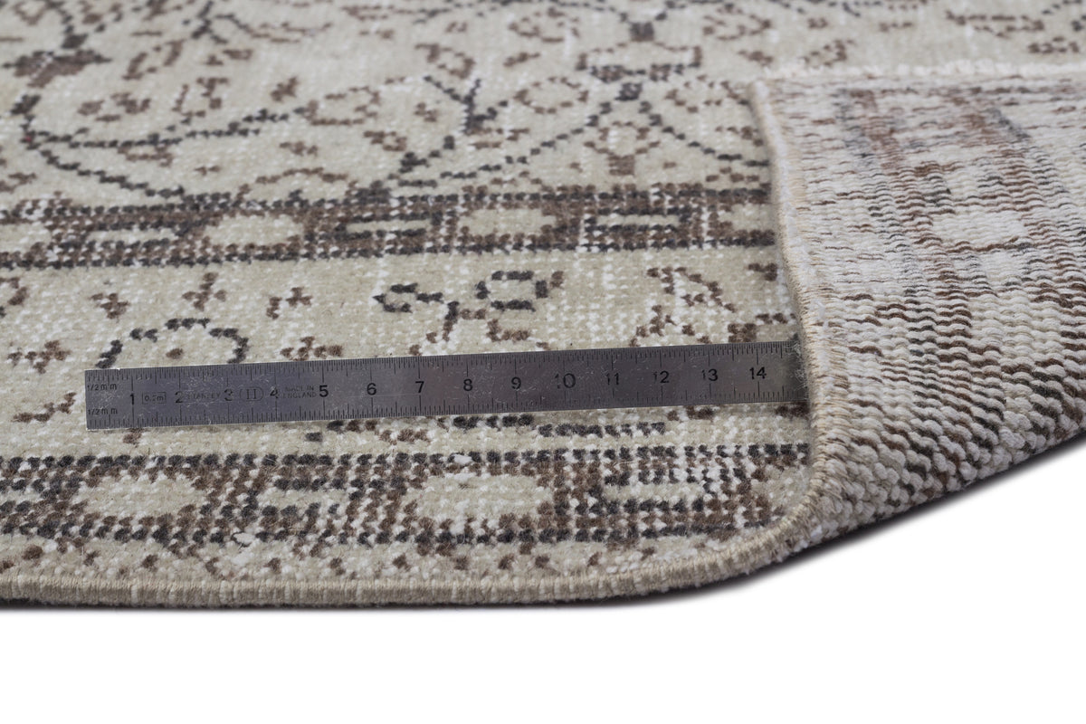 Beige and brown distressed traditional rug with a floral medallion pattern, shown with a metal ruler for scale.