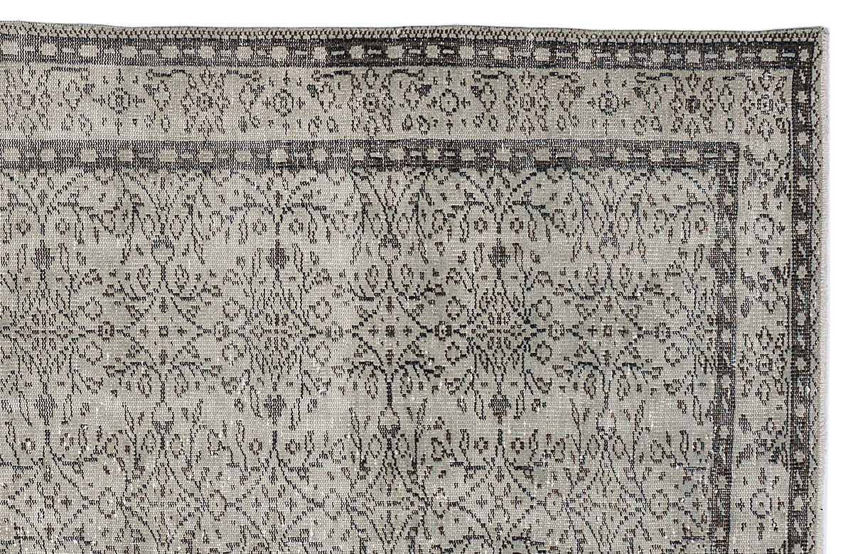 Grey and charcoal distressed rug with a traditional floral medallion pattern and a geometric border.