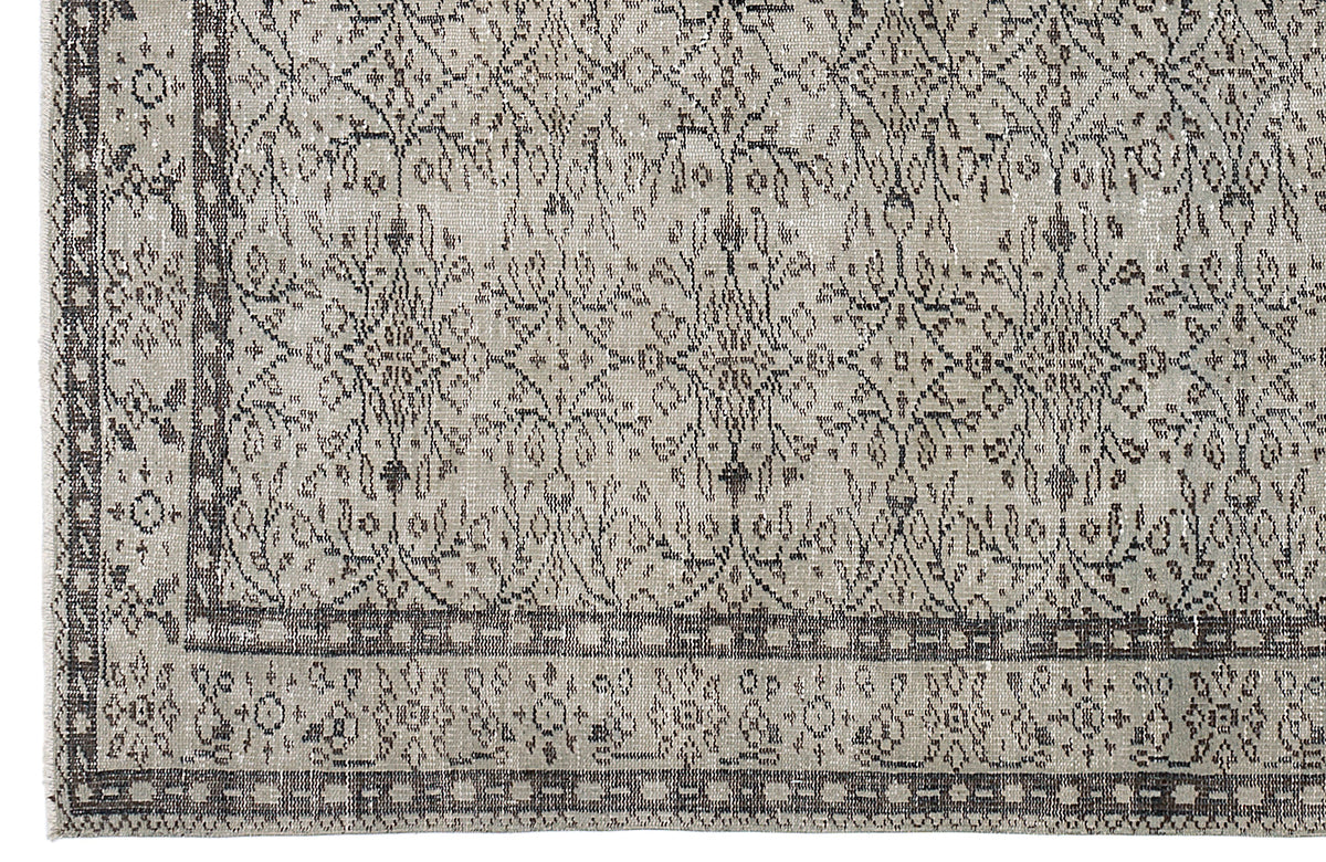 Beige and charcoal grey rug with a distressed traditional floral medallion pattern and a geometric border.