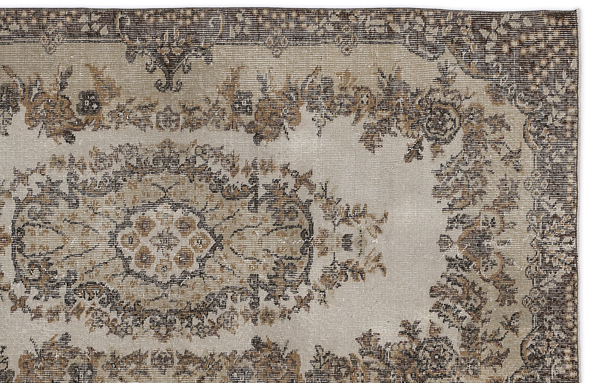 Distressed beige and brown vintage-style rug with a central floral medallion and ornate border.