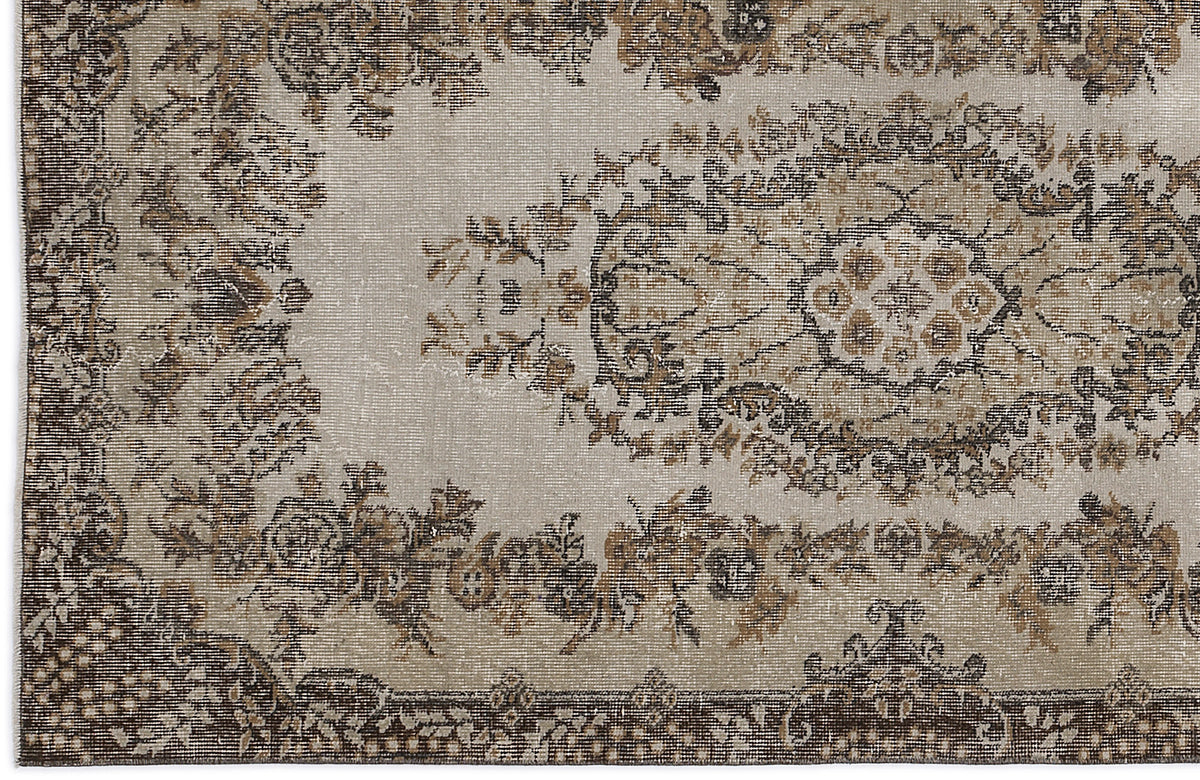 Beige and brown vintage-style rug with a distressed floral medallion pattern and ornate border.